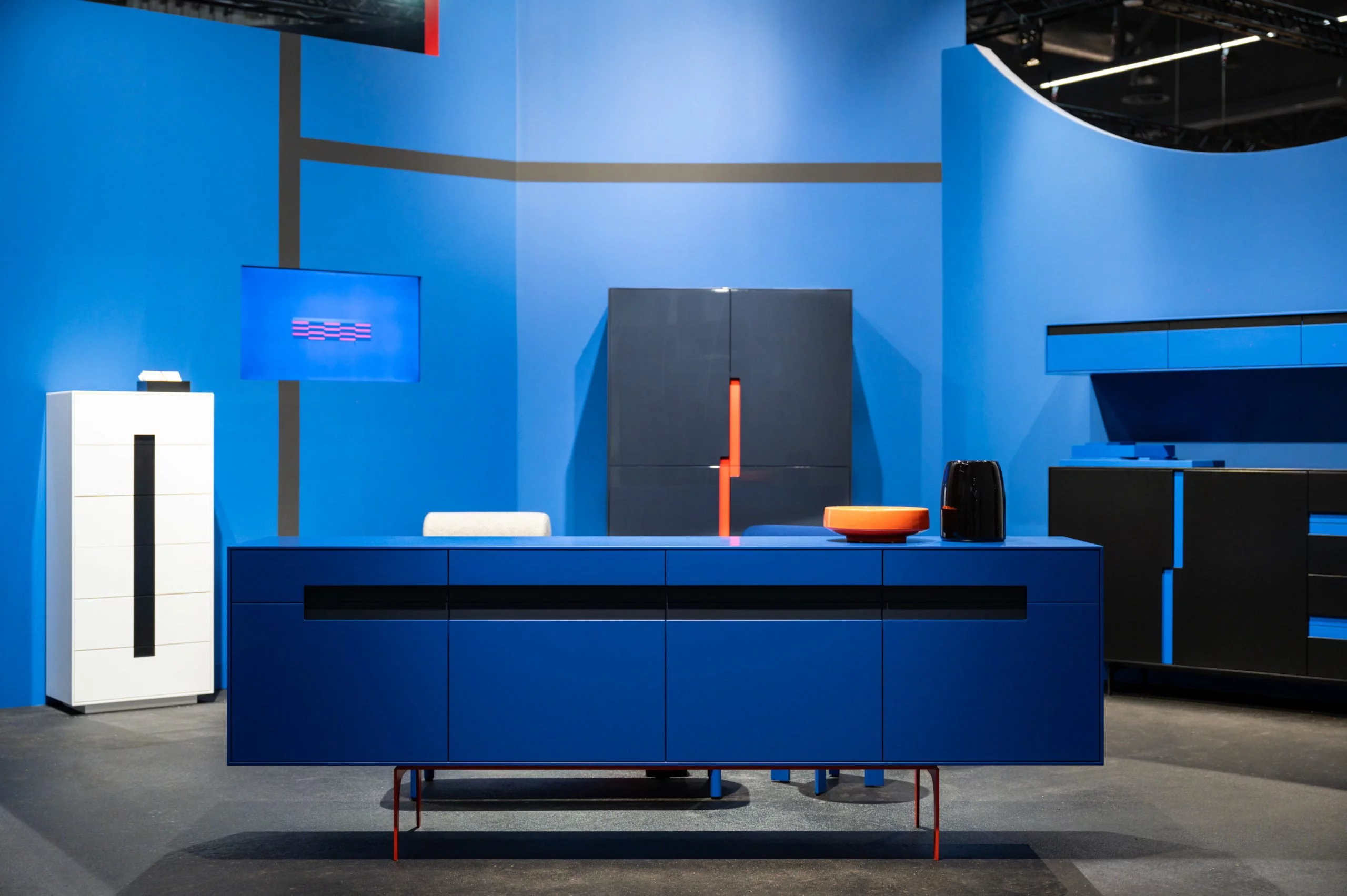 Ein stilvoller Messestand von Schönbuch auf der imm cologne Messe, präsentiert Möbel-Design in ansprechenden Farben, fotografiert von einem renommierten Fotografen aus Düsseldorf. Die Farben Blau und Orange dominieren.