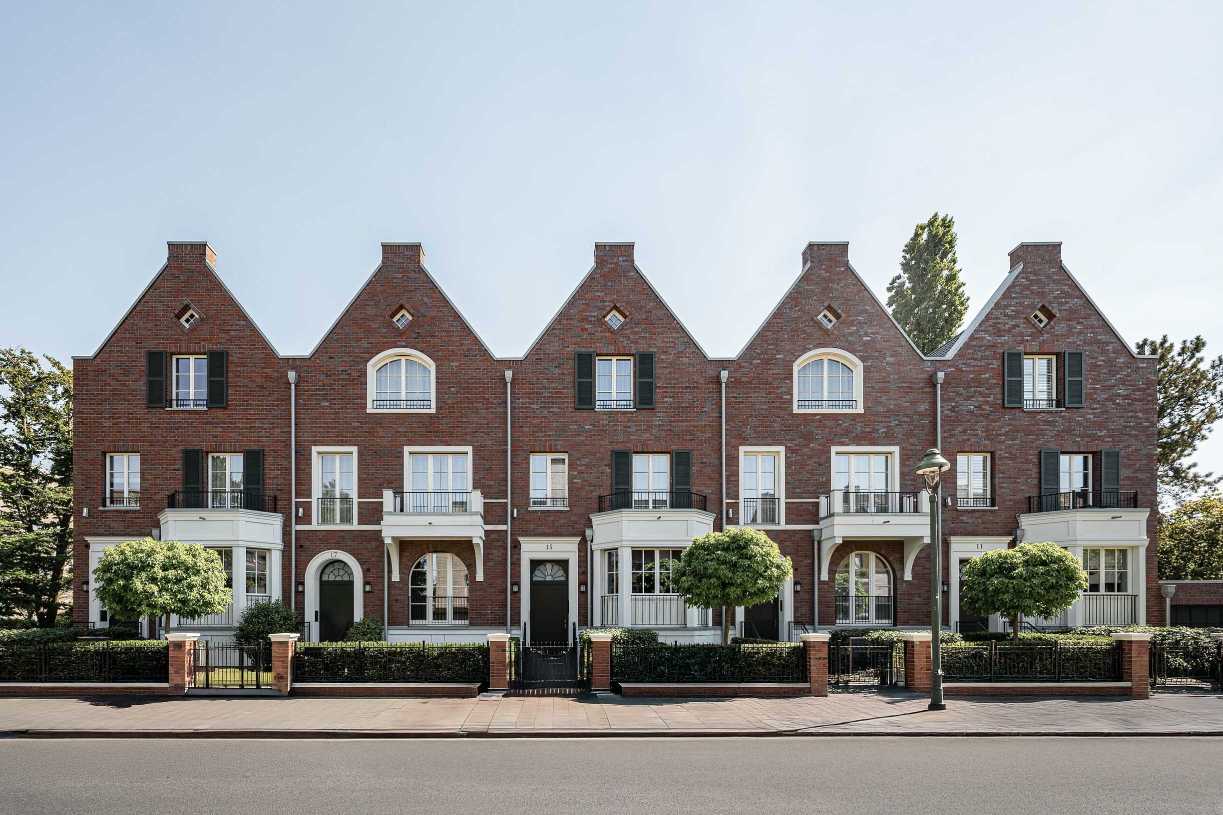 Immobilienfotografie einer Reihe von Backstein-Stadthäusern mit Giebeln, Erkern und Fensterläden bei Tageslicht in Düsseldorf.