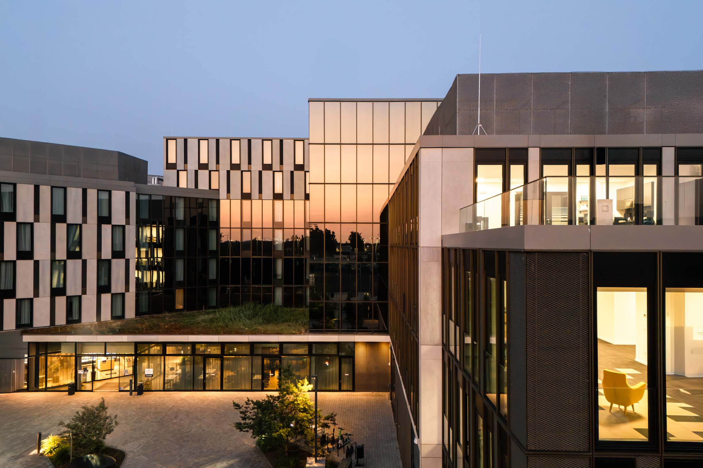 Northgate - Vogelsanger Weg Moderner Bürokomplex mit Glasfassaden und beleuchteten Innenräumen in der Dämmerung, Blick in einen Innenhof. Northgate Düsseldorf